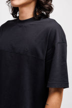 Ink Black | On Model Side Person wearing a black t-shirt with a brand logo on a plain background