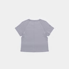 Chiseled Stone | Back A light gray short-sleeve crop top shown from the back, featuring a central seam and raglan-style shoulder seams, on a solid off-white background.