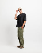 Ink Black | A model wearing a black oversized t-shirt, olive green cargo pants, and brown sneakers, posing against a plain white studio background.