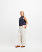 Deepwater Navy | A woman modeling a sleeveless navy top and off-white wide-leg pants against a plain white studio background.