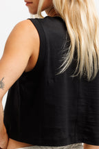 Ink Black | Close-up back view of a woman wearing a black sleeveless cropped tank top, showing the fabric and shoulder straps against a plain light background.