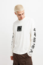 Cougar Milk | On Model Side White Westbeach long sleeve tee with a black heritage graphic featuring a light bulb, a skateboard board, and classic Westbeach iconography on the sleeves. 