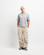 Chiseled Stone | On Model Full Front A model stands against a plain white studio background wearing a light gray short-sleeve t-shirt, beige cargo pants, and dark sneakers.