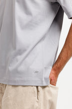 Chiseled Stone | On Model Side Detail Close-up of a person wearing a light gray short-sleeve t-shirt and beige pants, with the hand in the pocket of the pants visible on the right side.