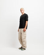 Ink Black | On Model Full Side A man modeling a black short-sleeve t-shirt and beige cargo pants against a plain white studio background.