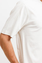 Cougar Milk | On Model Front Detail Close-up of a person wearing a plain white short-sleeve t-shirt against a light gray background.