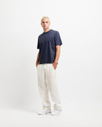 Deepwater Navy | On Model Full Front A man modeling a dark navy blue short-sleeve t-shirt and off-white linen pants against a clean white studio background.