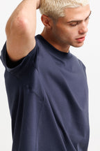 Deepwater Navy | On Model Side Detail A close-up of a man wearing an oversized navy blue t-shirt, showing the side and back of the garment against a plain light background.