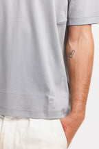 Chiseled Stone | On Model Front Detail Close-up of a person wearing a light gray short-sleeve t-shirt and off-white pants, showing the side of the torso and arm with a small heart tattoo.