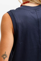 Deepwater Navy | Close-up back view of a person wearing a sleeveless navy top, showing the shoulder, upper back, and a small tonal logo near the lower left side.