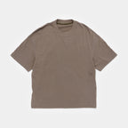 Cabin Smoke | Front A short-sleeve crewneck t-shirt in a muted taupe-brown color, featuring a small tonal logo on the left chest and a small circular logo near the hem, laid flat against a light gray background.