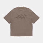 Cabin Smoke | Back A brown short-sleeve t-shirt shown from the back, featuring a tonal graphic of three surfers carrying surfboards across the upper back.