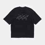 Ink Black | Back A black short-sleeve t-shirt shown from the back, featuring a dark gray graphic print of three surfers riding large waves across the upper back.